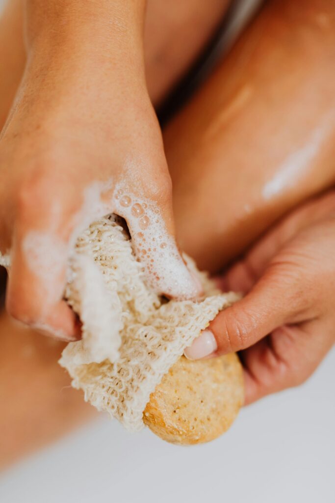 Close-up of a woman using a natural sponge and soap for exfoliation, embracing relaxation and body care.