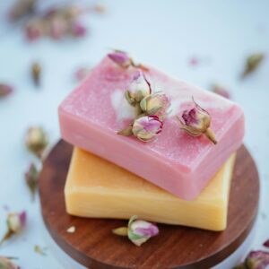 Artistic shot of stacked handcrafted soaps adorned with dried rose buds on a wooden stand.