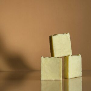 Three handmade soap bars artfully stacked on a reflective surface with neutral background.